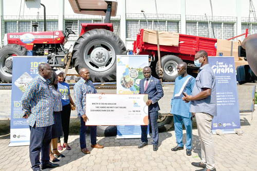  Mr Michael  Tetteh Voetagbe (4th from left), General Manager, Human Resource  and  Administration of the EXIM Bank, presenting  the tractor and cheque to  Dr Yaw Frimpong Addo (3rd from right), Deputy Minister of Food and Agriculture, at the ceremony in Accra. Those with them include some staff of the EXIM Bank and the Ministry of Food and Agriculture