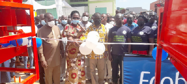 Ms Justina Owusu-Banahene (2nd from left), the Bono Regional Minister, being assisted by Mr Daniel Sackey (middle), the Managing Director of Ecobank, to cut the tape to commission the dehuskers and the articulated truck