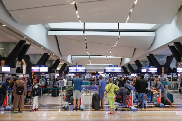 Travellers queue at a check-in counter at OR Tambo International Airport in Johannesburg after several countries banned flights from South Africa [Phill Magakoe/AFP]