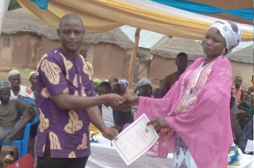 Mr  Mohammed Ali, Assembly man for Gbanjong Electoral Area, presenting a certificate to a beneficiary