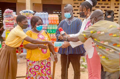  Ms Eunice Aba Sackey (2nd from right), presenting the items to Mrs Mariam Teiko, while  some teachers and pupils of the school look on
