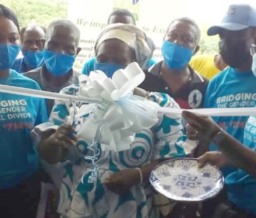 Madam Beauty Fiagbenu (middle), Chairperson for the programme, cutting the tape to inaugurate the project at Akode