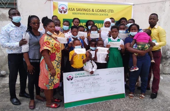 Mr Ahiadome (left), Madam Rosina Aku Owusu (2nd left), Krunom Area Manager, and some parents in a group photograph with the beneficiaries at Kronum.