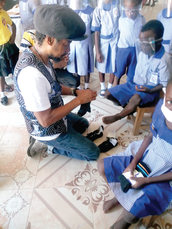  Mr Taj Weekes assisting one of the children to wear his shoes
