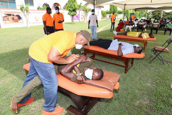 Dr Bryan Cox (left)  Chief Executive Officer of Spinal Clinic Limited, taking a beneficiary through a chiropractic session at Lashibi near Accra. Picture: Gabriel Ahiabor