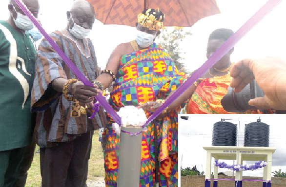 •Obrempong Sintim Poku (in cloth) being helped by other dignitaries to cut the tape to inaugurate the water facility. INSET: The mechanised borehole with two poly tanks ready for inauguration. : Pictures: SAMUEL KYEI-BOATENG