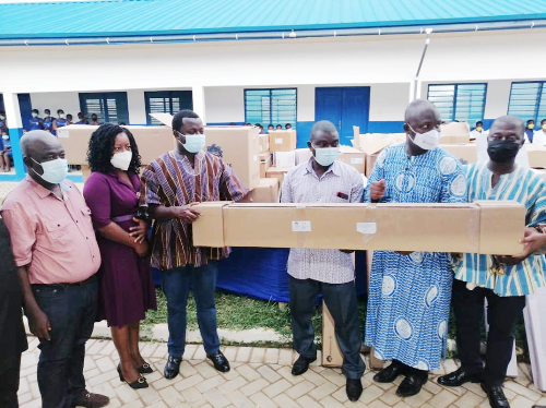  Rev John Ntim Fordjour (3rd left) presenting an equipment to Mr Festus Mensah (2nd right), headmaster of Assin South SHS, while other teachers look on
