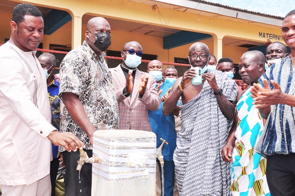 Mr Francis Poku (2nd left), CEO of Afriwave Telecom, and some elders of the community look on as Nana Osei Yaw, chief of Ekye-Amanfrom, takes a sip of the water after the facility was commissioned 