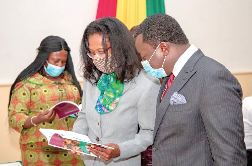 Rev Ntim Fordjour, Deputy Minister of Education, reading a book with Rasheena Reid, Head of USAID Learning, at the launch of Transition to English (T2E) Plus Steering Committee