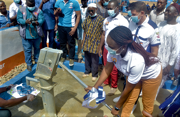 Akua Mensah, People and Culture Director of World Vision, pumping water out of the borehole while other officials look on 