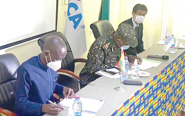 From left: Dr Franklin Asiedu Bekoe of the GHS and Kwame Asuah Takyi,  Comptroller General of the GIS, sign the documents for the items, while Araki Yasumichi, the JICA Chief Representative, looks on