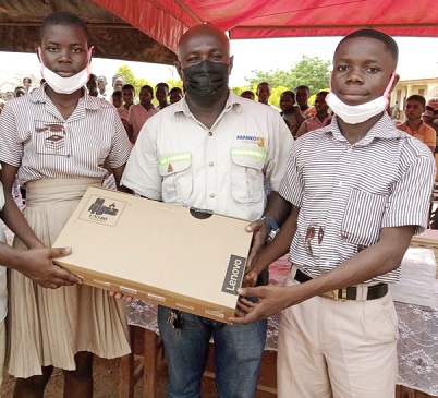 Kwabena Kwaakye (middle), Unit Manager, Land Access and Social Investment of Asanko Gold Ghana Limited, presenting the laptop to students of Kumpese for winning the JHS contest