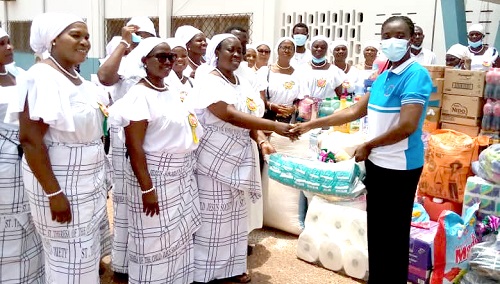  Benedicta Carr (left), President, St. Theresa of the Child Jesus, Adenta, presenting the items to Mary Rhondi Asia, Senior Nursing Officer, Pantang Hospital, while other members of the society look on