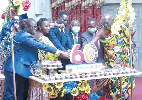 Dr Yaw Adutwum (middle),  Minister of Education, being assisted by other dignitaries to cut the 60th anniversary cake