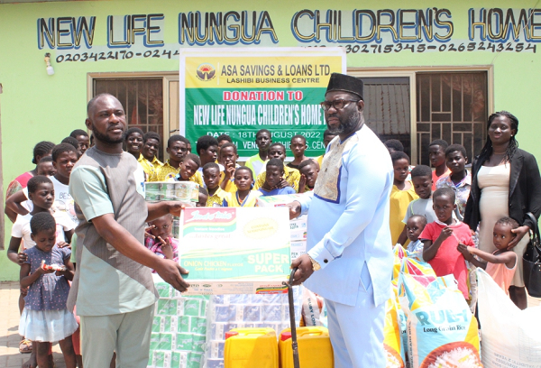 Mr Eugene Owusu Biney (left), Ashaiman Area Manager of ASA Savings and Loans handing over items to Nii Afotey Botwe, Chief of Otinnor - Nungua and Manager of the New Life Children's Home International as the children in the orphanage looked on.