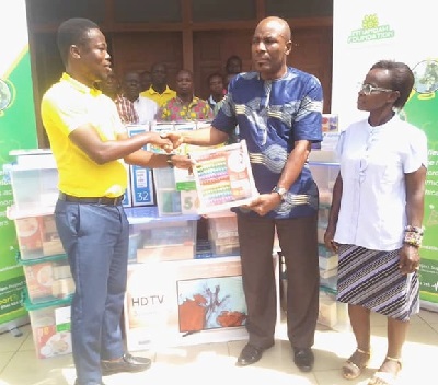 Shiva Oppong Banahene (left) presenting the TV sets and educational materials to Emmanuel Attipoe (second from right)