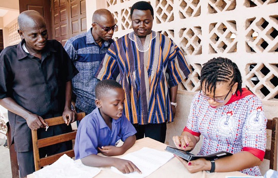 Rev. John Ntim Fordjour (2nd from right), Deputy Minister of Education,  observing a  pupil taking the standardised test