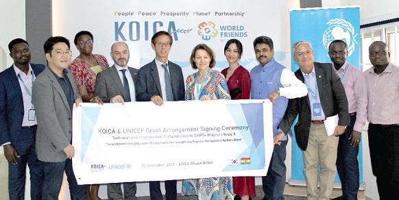 Anne-Claire Dufay (arrowed), UNICEF Country Representative, and Moo Heon Kong (3rd from left) holding the signed poster with other officials after the signing