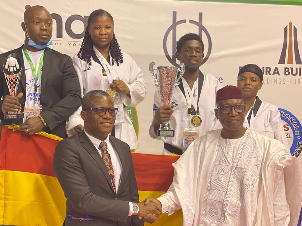Mr Fredrick Lartey Otu (left) being congratulated by Mr Ide Issaka, President of African Taekwando Union, while the athletes displays their trophies and medals