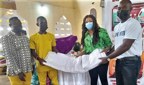 Mr Felix Kissiedu-Addi (right), Executive Director of United Way Ghana, assisted by Miss Faustina Abbey (2nd from right), Country Director of Engage Now Africa, handing over tie and dye items to Mr Dan Bright (2nd from left), the assembly member for Kokrobite 