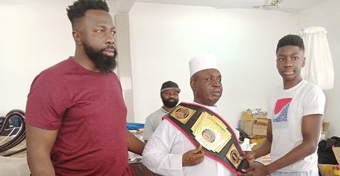 Joseph Awinogya Junior(right) decorates Alhaji Inusah with his belt while his father, Joseph Awinogya Snr..,assists