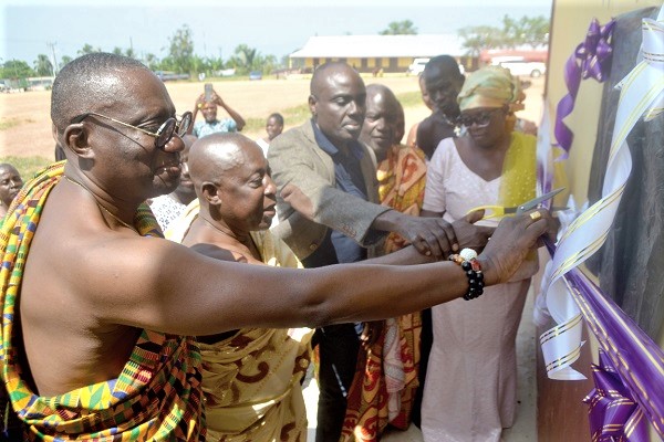 Mr Siisi Crentsil (left), the Nsona Family Head, being assisted by Osabarima Otsibu VI (middle), the Omanhene of the Enyan Denkyira Traditional Area,  and other guests, to commission one of the schools