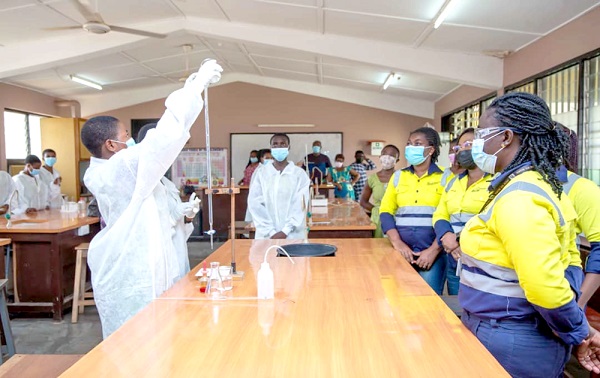Scientists instructing some female students through a laboratory demonstration 