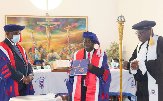 Prof. Ebenezer Owusu (middle) displaying the statutes of the university. He is flanked by Rt Rev. Prof. Joseph Obiri Yeboah Mante (right), Moderator of General Assembly, PCG, and Justice Prof. Nii Ashie Kotey (left), Chair of the University Council