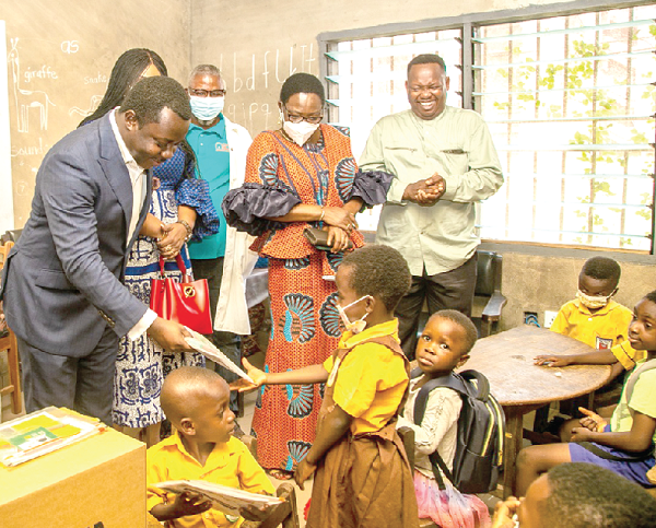 Rev. John Ntim Fordjour (left) presenting a book to a pupil during the  visit, while officials of the GES look on
