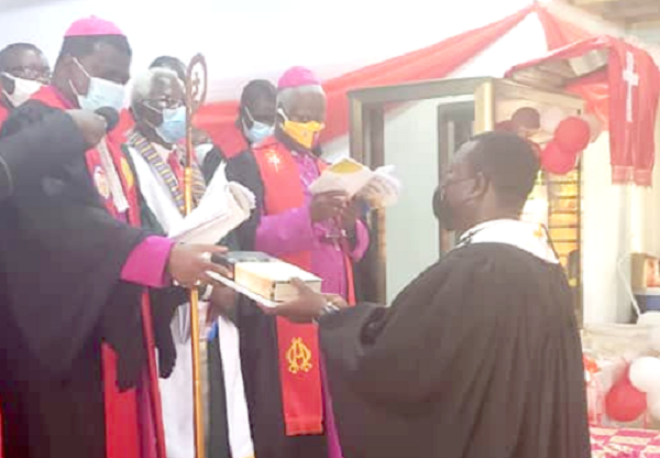 Rt Rev. Emmanuel Asare-Kusi handing over a Bible and the constitution of the church to Very Rev. Eku as a symbol of authority