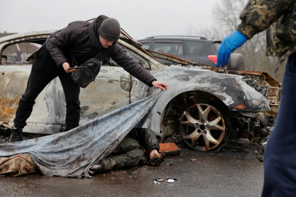 A funeral service worker uncovers a a civilian's body as Russia's attack on Ukraine continues, in the village of Nova Basan, Chernihiv region, April 1 [Serhii Nuzhnenko/Reuters]
