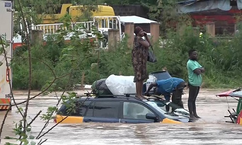 Passengers on the roof of a partially submerged taxi