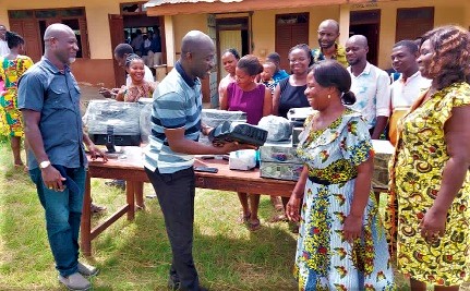 Dr Dickson Okorie Mireku (2nd from left), President of the 1995 Year Group of the Nkwatia Presbyterian JHS, presenting one of the items to Dorcas Otchere (2nd from right), Headmistress of the Nkwatia Presbyterian JHS