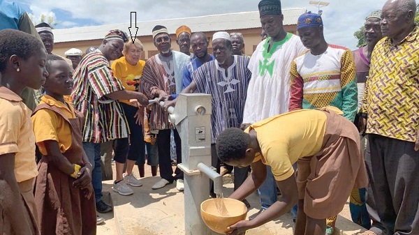 Karen Flewelling (arrowed) being assisted by some chiefs and elders to pump water out of one of the boreholes constructed at the Yua Taribisi basic school