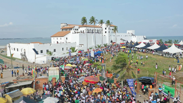 A prossesion of chiefs and people of Edina through the streets of Elmina. Behind is the historic Elmina Castle