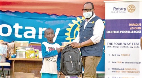 A pupil ( left) receiving his share of the educational materials from Mr Nathaniel  Northa, the Service Project Director of the Rotary Club of Tarkwa.