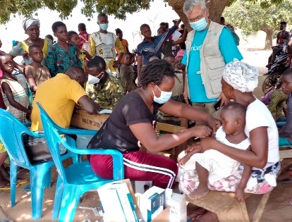A  health official vaccinating a child, while Mr Bhanu Pathak, UNICEF Chief Field Officer, looks on