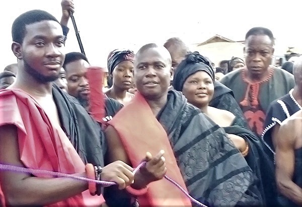 Nene Tetteh Djaba Agbleze IV (middle), the new Plau Divisional Chief, pulling the rope to unveil the funeral banner of his predecessor at the Somanya Roundabout
