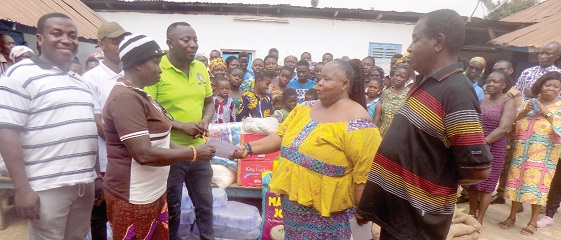 Madam Philomena Asantewaa Agyei (2nd from right) thanking Madam Yaa Amoanimaa after receiving the gift while officers of the Kade Cocoa District of COCOBOD look on.