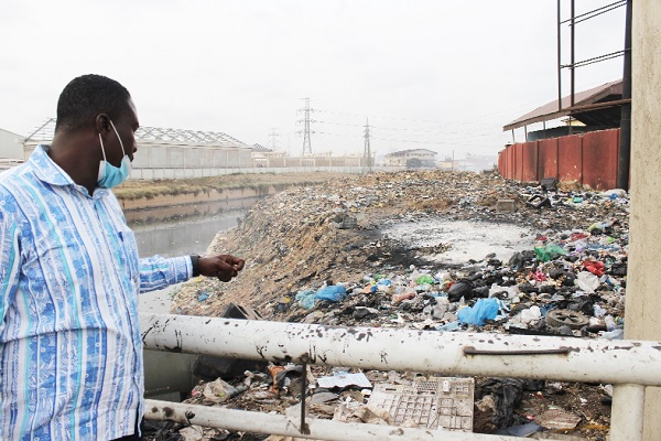 Kester Aburam Korankye, a Staff Writer of the Daily Graphic, pointing at the filth in the drain