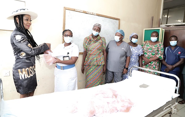 Stephanie Benson presenting the cheque to Mrs Augusta Gyening, the Senior Nursing Officer of the Surgical Oncology Unit. Looking on are some breast cancer survivors and staff at the unit