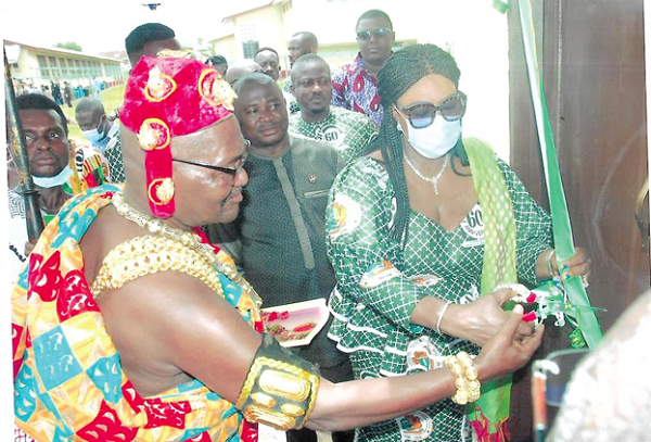 Tina Gifty Naa Ayetey Mensah (right) being assisted by Nana Dwamena Akenteng to cut the tape to inaugurate the new CHPS compound while Alexander Akwasi Acquah, Oda MP, looks on.  Picture: SAMUEL KYEI-BOATENG