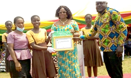  Charles Oware-Tweneboah (right), DCE of Fanteakwa North and Gloria Aggrey Kilson (third right) the Education Director presenting a framed certificate to one of the participating schools