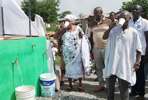 Nana Awo Korkor (left), Mawerehemaa of Awherease, and Nana Kwasi Fante (right), Odikro of Koko Junction, tasting the water after the inauguration. Looking on are community members as well as other dignitaries