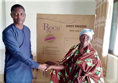 Sampson Tetteh Kpankpah, the Ada West District Chief Executive, presenting a deep freezer to Comfort Abayateye, a visually impaired woman