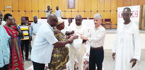 Cafer Tepeli (2nd from right), President of TUDEC Development, being assisted by Michael Okyere Kofi Baafi (middle), MP for New Juaben South, to present the food items to Yaa Nkrumah (2nd from left), one of the beneficiaries.