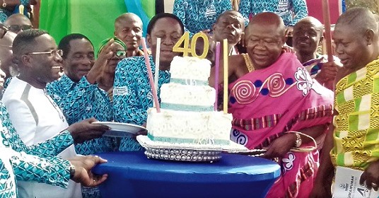 Dr Kwabena Duffour (3rd from left), first Board Chairman of the bank, and Barima Sarfo Tweneboa Kodua (2nd from right), the Paramount Chief of Kumawu, being assisted to cut the anniversary cake 
