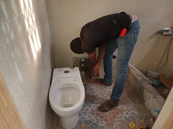 A biodigester technician fixing a toilet seat