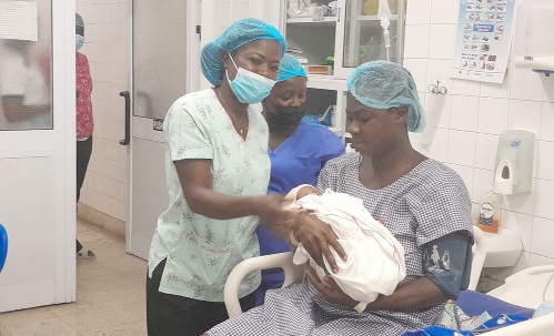 Faustina Donkor (left), Senior Staff Midwife in charge of the afternoon shift of the Delivery Ward of the Eastern Regional Hospital, admiring the baby delivered by Esther Dede