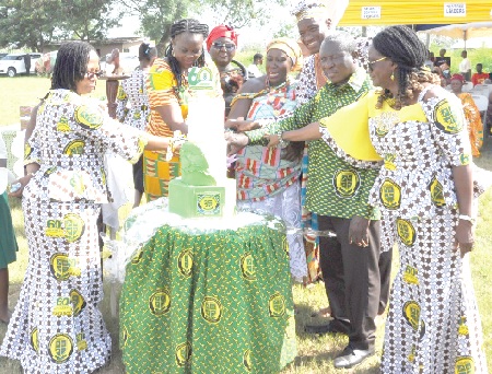 Sheila Naah Boamah (2nd from left) being assisted by Mamaga Adzesu II (arrowed), Paramount Queenmother of the Sokpoe Traditional Area; Seth Agbi (2nd from right), South Tongu DCE, and other dignitaries to cut the anniversary cake